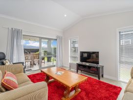 A living room with a wooden coffee table a red rug and a TV on a stand at Tide and Tranquility - Whitianga Holiday Home in Whitianga