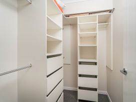 A walk in closet with shelves drawers and hanging rods at Tide and Tranquility - Whitianga Holiday Home in Whitianga