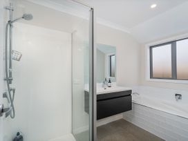 A bathroom with a shower enclosure a bathtub a wall-mounted sink and a frosted window at Tide and Tranquility - Whitianga Holiday Home Whitianga