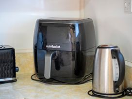 A kitchen countertop with a black Nutribullet air fryer a silver electric kettle and part of a black toaster at Cosy Crib - Te Anau Holiday Home in Te Anau