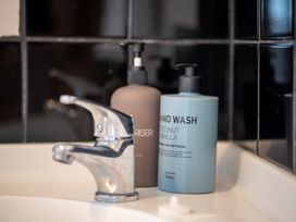 A bathroom sink with a chrome faucet and two pump bottles of hand wash on the counter at Cosy Crib - Te Anau Holiday Home in Te Anau
