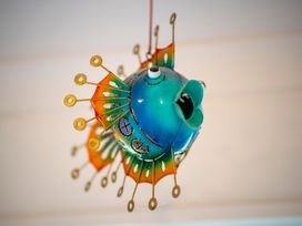 A colorful metal fish hanging decoration with blue and orange fins in a room at Cosy Crib - Te Anau Holiday Home in Te Anau