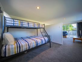 A bedroom with a bunk bed and a view into a living room with a couch and coffee table at Relaxing Kiwi Bach - Te Anau Holiday Home