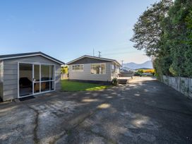 A driveway with two single-story buildings and trees on the side at Relaxing Kiwi Bach in Te Anau