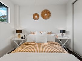 A bedroom with a bed with checkered bedding two bedside tables with lamps and two wall decorations at Remarkable QT  Queenstown Holiday Home