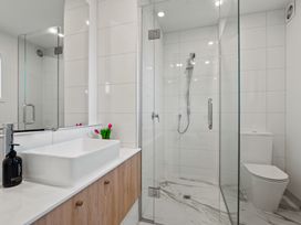 A bathroom with a rectangular sink on a wooden vanity a glass-enclosed shower and a toilet at Remarkable QT  - Queenstown Holiday Home in Queenstown