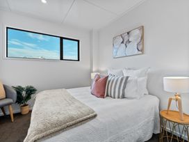 A bedroom with a bed pillows a side table with a lamp a chair and a window showing a mountain view at Remarkable QT  Queenstown Holiday Home