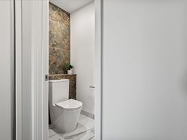 A small bathroom with a toilet marble wall tiles and a plant on a shelf at Remarkable QT  Queenstown