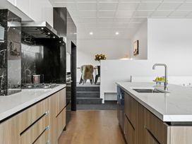 A modern kitchen with wooden cabinets a white countertop and a black marble backsplash at Remarkable QT  Queenstown Holiday Home in Queenstown