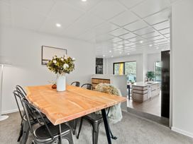 A dining area with a wooden table and black chairs next to an open kitchen at Remarkable QT  - Queenstown Holiday Home in Queenstown