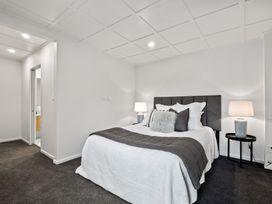 A bedroom with a double bed with white and gray bedding and bedside tables with lamps at Remarkable QT  Queenstown Holiday Home in Queenstown