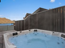 A hot tub with a view of mountains and lake at Remarkable QT - Queenstown Holiday Home