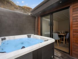 A hot tub on an outdoor patio at Remarkable QT - Queenstown Holiday Home