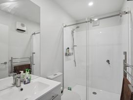 A bathroom with a sink, mirror, visible toilet, glass shower enclosure, and towel racks with brown towels at Alex Vineyard - Alexandra Holiday Home in Alexandra