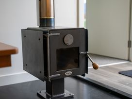 A black metal wood stove with a chimney pipe in a room at Alex Vineyard - Alexandra Holiday Home in Alexandra