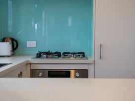 A kitchen countertop with a gas stove toaster kettle and white cabinets at Alex Vineyard - Alexandra Holiday Home in Alexandra