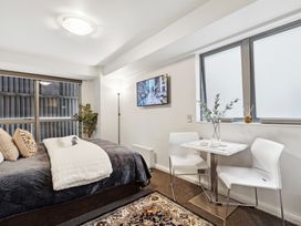 A bedroom with a bed pillows a small table with two chairs and a television on the wall at Cityscape on White Auckland Central Studio in Auckland Central