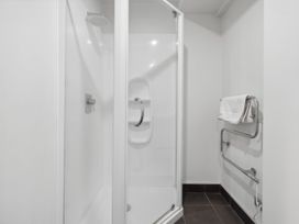 A shower enclosure with a glass door and a towel rack with a white towel in a bathroom at Cityscape on White - Auckland Central Studio in Auckland Central