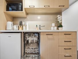 A kitchen counter with a microwave oven a kettle a toaster utensils dish soap an open dishwasher and drawers at Cityscape on White - Auckland Central Studio in Auckland Central