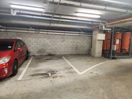 A parking garage with a red car and storage tanks at Cityscape on White - Auckland Central