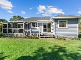 A backyard view of a grey house with a porch and windows at Bell Cottage - Oakura Holiday Home in Oakura