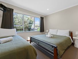 A bedroom with two beds covered with green blankets and white towels on them at Bell Cottage - Oakura Holiday Home in Oakura