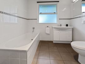 A bathroom with a bathtub sink with cabinet and toilet at Bell Cottage - Oakura Holiday Home in Oakura