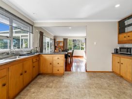 A kitchen with wooden cabinets and countertops next to a dining area with a table and chairs at Bell Cottage - Oakura Holiday Home in Oakura