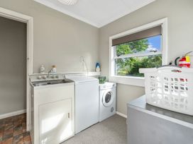 A laundry room with a washing machine dryer sink and a laundry basket on a counter at Bell Cottage - Oakura Holiday Home in Oakura
