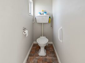 A small bathroom with a toilet and toilet paper on the wall at Bell Cottage - Oakura Holiday Home in Oakura