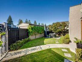 A backyard with a black fence patio table and chairs and a pathway at Coastal Charm - Napier Holiday Home in Napier