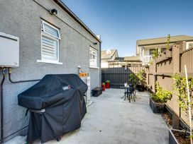 An outdoor patio area with a covered barbecue grill small table and two chairs and potted plants at Coastal Charm Napier Holiday Home in Napier