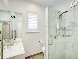 A bathroom with a sink and mirror toilet and shower with glass door at Coastal Charm - Napier Holiday Home in Napier