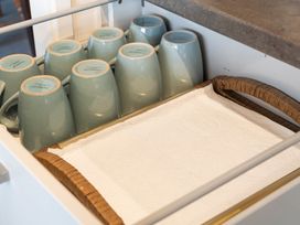 A drawer with upside down ceramic mugs and a wicker tray with paper towels at Waiake Family Retreat - Auckland Holiday Home in Auckland