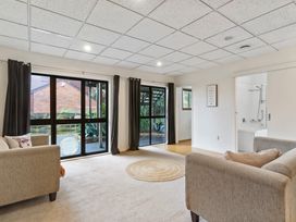 A living room with two sofas a round rug and large windows with dark curtains at Waiake Family Retreat in Auckland
