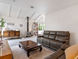 A living room with brown leather sofas a wooden coffee table wood stove and a wooden sideboard at Waiake Family Retreat - Auckland Holiday Home in Auckland
