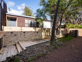An outdoor area with a deck and brick wall at Waiake Family Retreat - Auckland