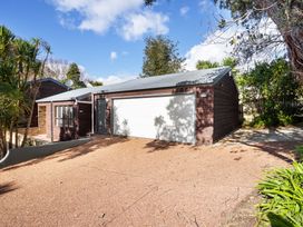 A house with a garage and shrubs at Waiake Family Retreat - Auckland