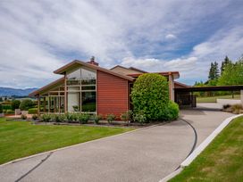 A modern house with large windows and a driveway surrounded by grass at Elderberry Wine - Wanaka Holiday Home Wanaka