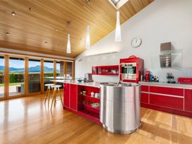 A kitchen with red cabinets a round stainless steel sink and wooden ceiling at Elderberry Wine - Wanaka Holiday Home in Wanaka