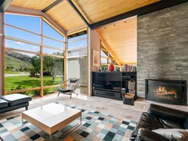 A living room with large windows a fireplace a television a chair and a coffee table at Elderberry Wine - Wanaka Holiday Home Wanaka