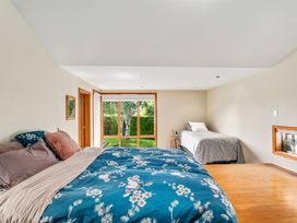 A bedroom with a double bed and a single bed near a window showing a garden at Elderberry Wine - Wanaka Holiday Home Wanaka