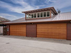 A building exterior with two wooden garage doors and a row of windows above at Elderberry Wine - Wanaka Holiday Home in Wanaka