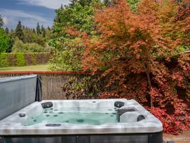 An outdoor hot tub with water surrounded by trees and plants at Elderberry Wine - Wanaka Holiday Home in Wanaka