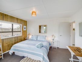 A bedroom with a bed and two side tables with lamps at Sunset Haven - Mahia Holiday Home in Mahia Peninsula