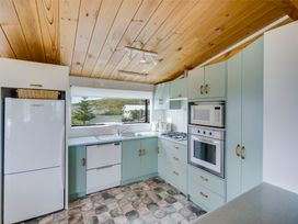 A kitchen with green cabinets white appliances and a wooden ceiling at Sunset Haven - Mahia Holiday Home in Mahia Peninsula