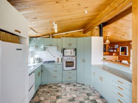 A kitchen with light green cabinets a gas stove an oven and a microwave at Sunset Haven - Mahia Holiday Home in Mahia Peninsula