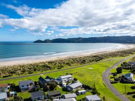 A coastal residential area with houses near a beach and a curved road at Sunset Haven - Mahia Holiday Home in Mahia Peninsula