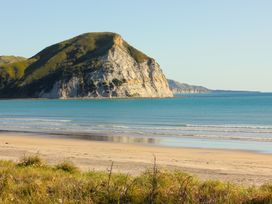 A beach with water and a mountain at Sunset Haven - Mahia Holiday Home Mahia Peninsula