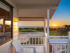 A balcony with a chair overlooking the sea at Sunset Haven - Mahia Holiday Home, Mahia Peninsula